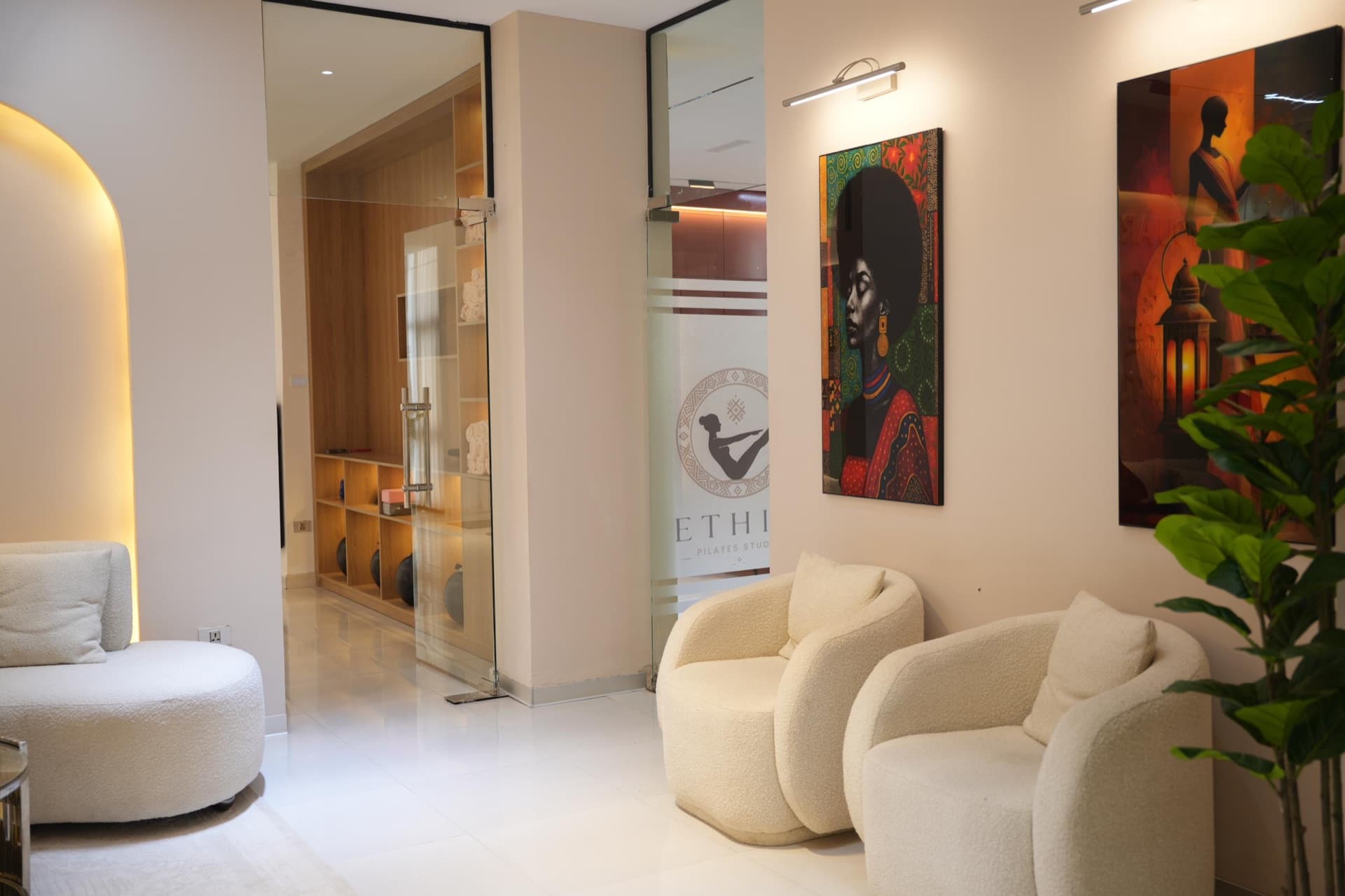 The quiet studio lounge with cream armchairs and African portrait art