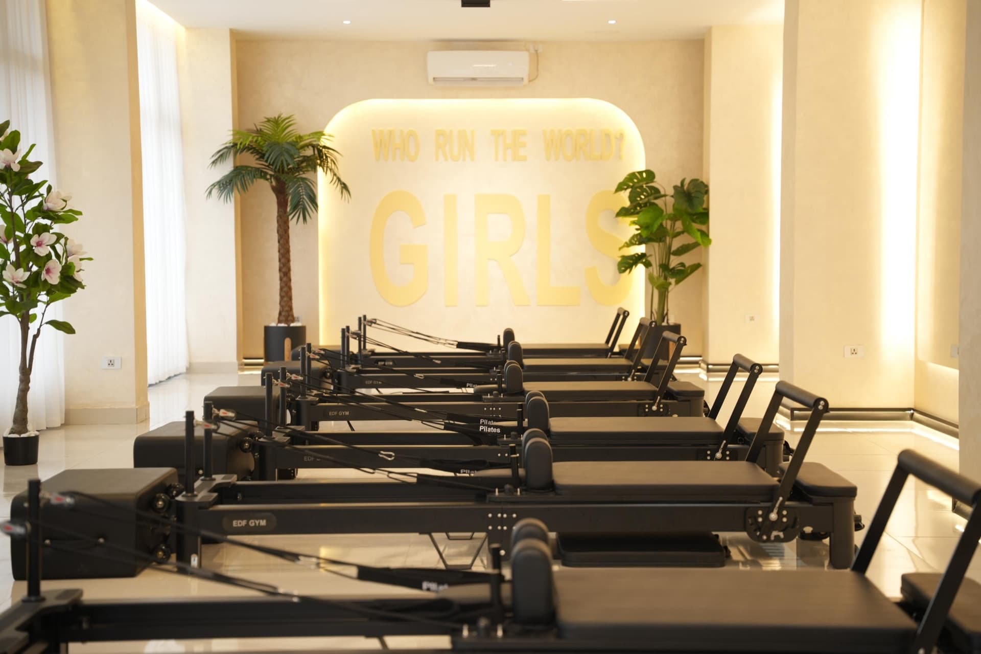 The empty reformer hall at rest beneath the brass 'who run the world — girls' lettering